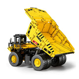 Camion benne basculante en briques jaunes et noires, benne relevée, pneus texturés